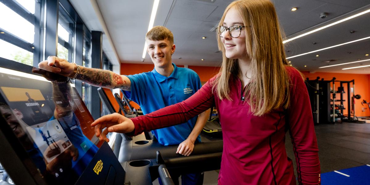 Fitness Attendant showing girl how to use the treadmill